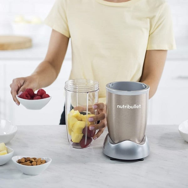 A person putting fruits on the blender jar to be crushed using the Nutribullet 900 Pro