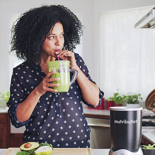 A beautiful woman sipping avocado smoothie from a Nutribullet RX 1700W jar