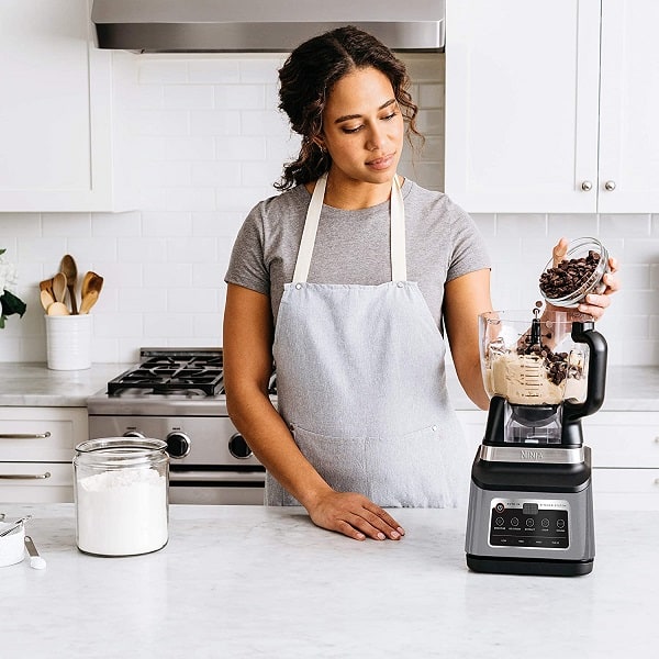 A woman using her favorite blender food processor to mix choco cookie dough