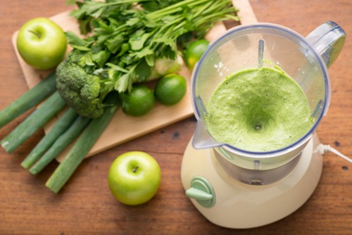 Green smoothie in a blender and ingredients