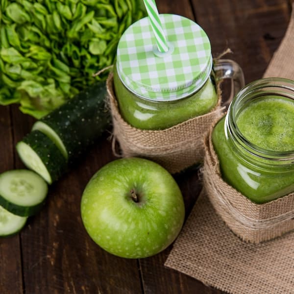 green apple smoothie beside of two clear glass jars